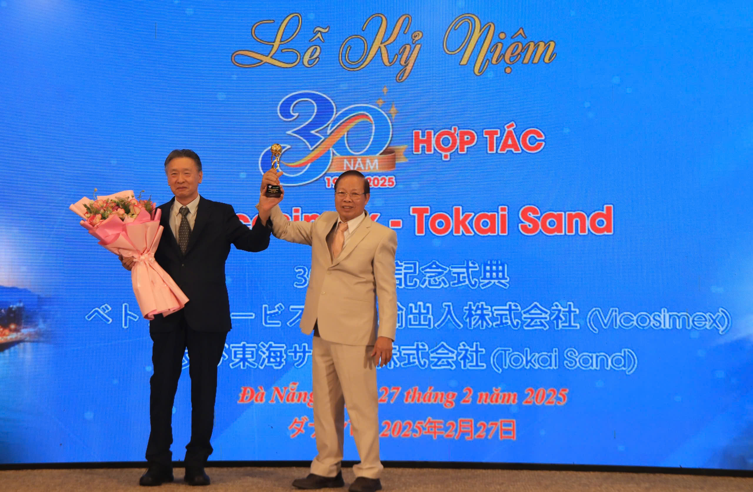 Ông Võ Văn Kiệt, Tổng Giám đốc Công ty Vicosimex (bên phải) cùng ông Tsukamoto Hiromi, Chủ tịch Công ty Tokai Sand (Nhật Bản) cùng nhau nâng cúp chúc mừng tại Lễ kỉ niệm 30 năm hợp tác.