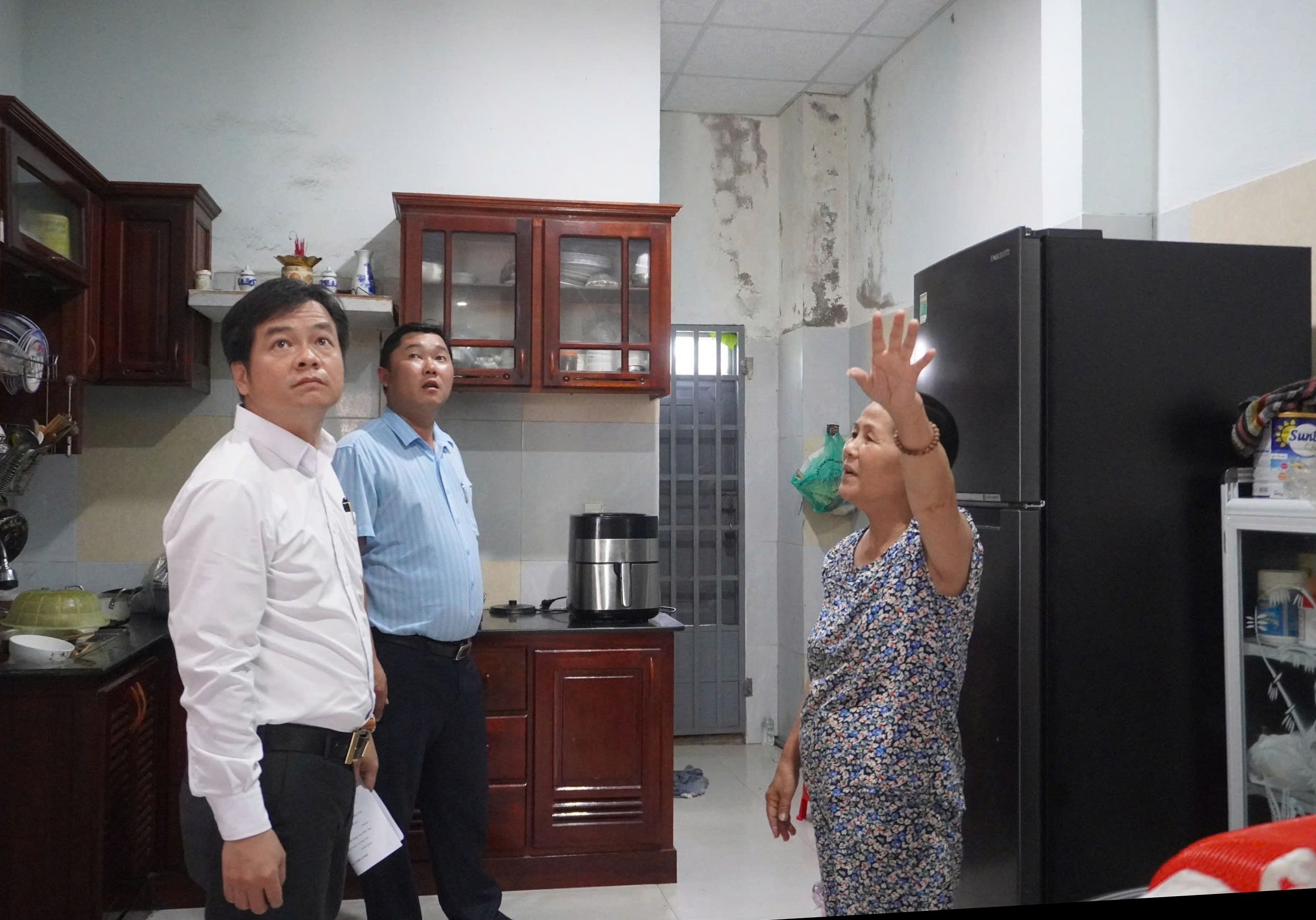 Ông Huỳnh Đức Vinh (bên trái) kiểm tra thực tế việc sửa chữa nhà ở cho gia đình chính sách trên địa bàn phường Mỹ An. Ảnh: HOÀNG NHUNG