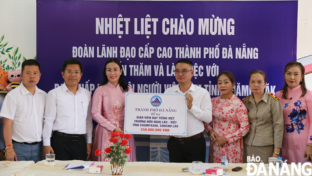 Phó chủ tịch UBND thành phố Nguyễn Thị Anh Thi (thứ 3 từ trái qua) trao hỗ trợ cho Hội người Việt Nam tỉnh Champasak 240 triệu đồng để hỗ trợ 2 giáo viên dạy tiếng Việt tại Trường Trung học Hữu nghị Việt – Lào. Ảnh: ĐẮC MẠNH