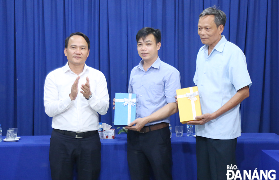 Phó Bí thư Thường trực Thành ủy Nguyễn Đình Vĩnh (bên trái) tặng quà 2 giáo viên người Việt Nam dạy tại tỉnh Attapeu. Ảnh: ĐẮC MẠNH 